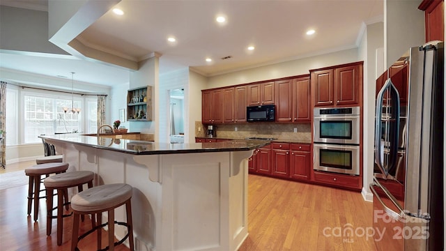 8605 Soaring Eagle Ln, Waxhaw, NC 28173 - kitchen featuring appliances with stainless steel finishes, crown molding, a breakfast bar, backsplash, and light wood finished floors