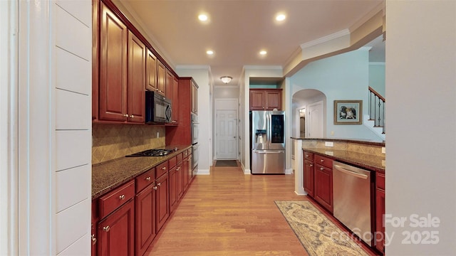 8605 Soaring Eagle Ln, Waxhaw, NC 28173 - kitchen with appliances with stainless steel finishes, arched walkways, light wood-style floors, backsplash, and ornamental molding