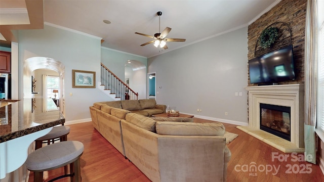 8605 Soaring Eagle Ln, Waxhaw, NC 28173 - living area with arched walkways, light wood-type flooring, a large fireplace, and crown molding
