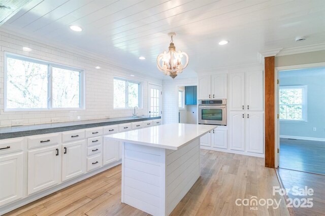 3921 Bon Rea Dr, Charlotte, NC 28226 - kitchen featuring stainless steel oven, a chandelier, light wood-style flooring, white cabinets, and a sink