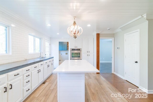 3921 Bon Rea Dr, Charlotte, NC 28226 - kitchen featuring stainless steel oven, a sink, a chandelier, ornamental molding, and white cabinetry