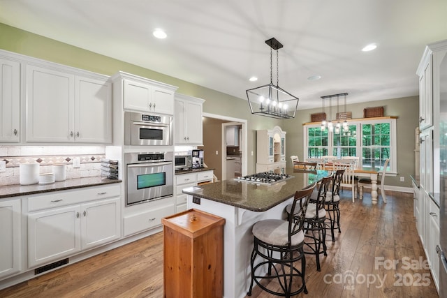 270 N St, Salisbury, NC 28147 - kitchen featuring appliances with stainless steel finishes, a kitchen island, white cabinetry, a kitchen bar, and wood-type flooring