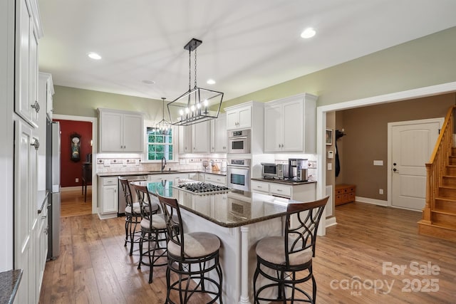 270 N St, Salisbury, NC 28147 - kitchen with stainless steel appliances, a sink, a breakfast bar area, a chandelier, and tasteful backsplash