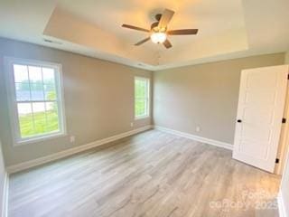1872 Terrain Dr NW, Conover, NC 28613 - unfurnished room featuring a tray ceiling, light wood finished floors, baseboards, and ceiling fan
