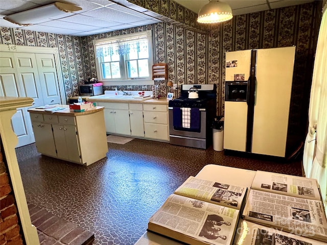 4689 Lakeview Acres Rd, Valdese, NC 28690 - kitchen featuring appliances with stainless steel finishes, wallpapered walls, light countertops, white cabinets, and a kitchen island