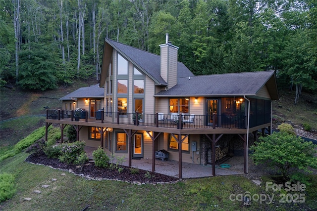 268 Trappers Run Dr, Burnsville, NC 28714 - rear view of house with a patio area, a deck, a shingled roof, a chimney, and a view of trees