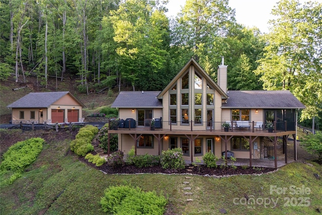268 Trappers Run Dr, Burnsville, NC 28714 - back of property featuring a chimney, a wooden deck, a garage, and an outbuilding