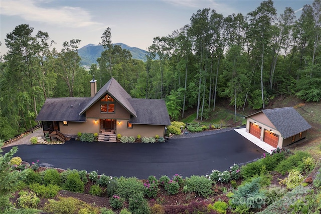 268 Trappers Run Dr, Burnsville, NC 28714 - view of front of house featuring an outdoor structure, a mountain view, a garage, a chimney, and a forest view
