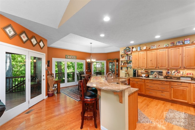 399 Stepping Stone Ln, Waynesville, NC 28786 - kitchen featuring a kitchen bar, light wood-style floors, recessed lighting, light stone countertops, and decorative light fixtures