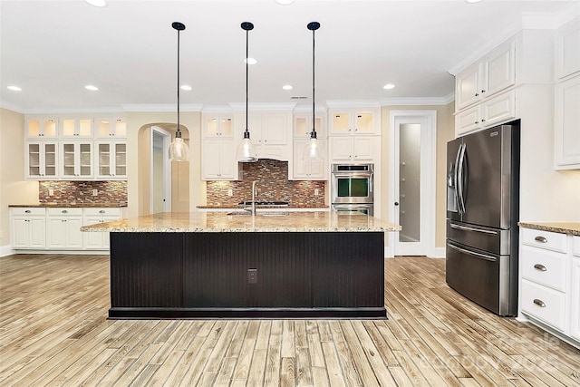 11052 Preservation Park Dr, Charlotte, NC 28214 - kitchen with stainless steel appliances, arched walkways, light wood finished floors, ornamental molding, and glass insert cabinets