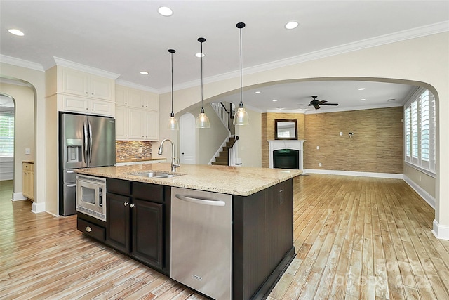 11052 Preservation Park Dr, Charlotte, NC 28214 - kitchen featuring appliances with stainless steel finishes, arched walkways, a sink, baseboards, and light wood-style floors