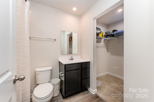 2037 Langer St, Charlotte, NC 28214 - bathroom featuring toilet, vanity, a walk in closet, wood finished floors, and baseboards