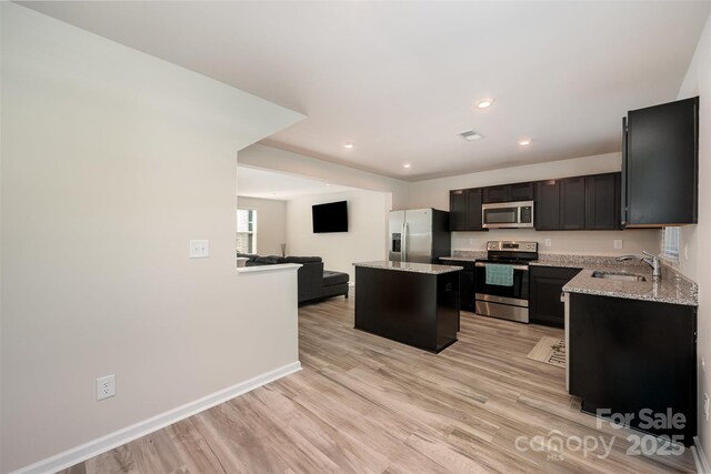 2037 Langer St, Charlotte, NC 28214 - kitchen featuring stainless steel appliances, a sink, a kitchen island, light wood-type flooring, and light stone countertops