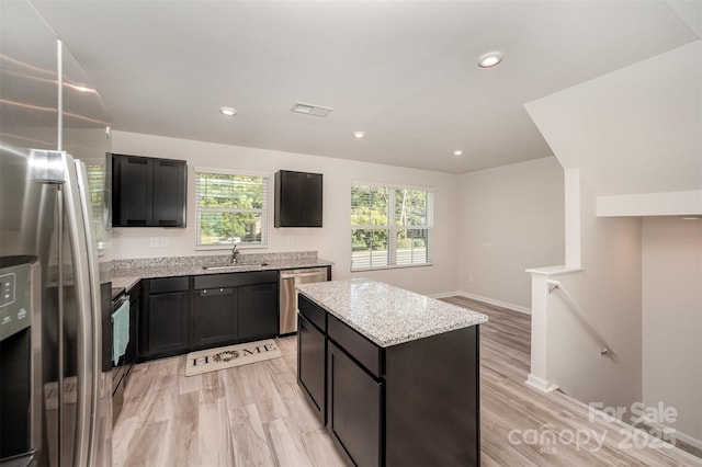2037 Langer St, Charlotte, NC 28214 - kitchen with appliances with stainless steel finishes, a sink, a kitchen island, light wood-style floors, and light stone countertops