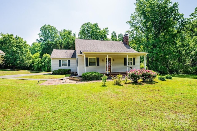 view of front of home with a chimney, covered porch, and a front lawn