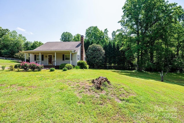 view of front facade with covered porch, a chimney, and a front yard