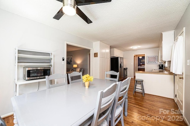 dining room featuring a ceiling fan, light wood-type flooring, and a textured ceiling