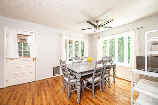 dining space featuring light wood-style floors, a textured ceiling, ceiling fan, and baseboards