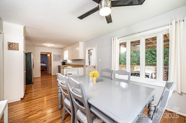 dining room with light wood-type flooring, a textured ceiling, and a ceiling fan