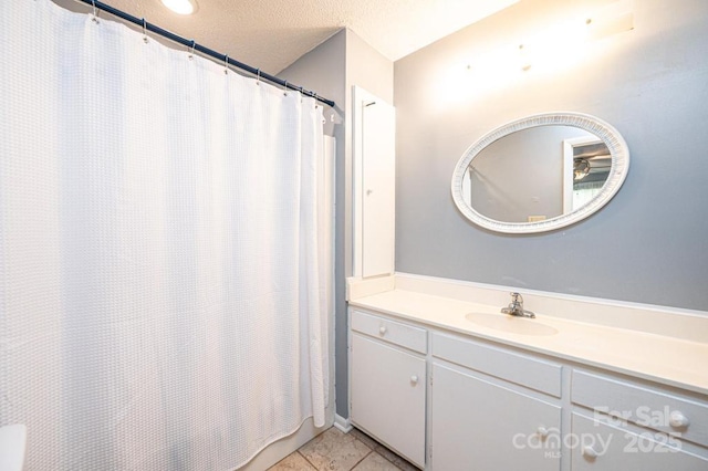 bathroom featuring a textured ceiling, tile patterned flooring, and vanity