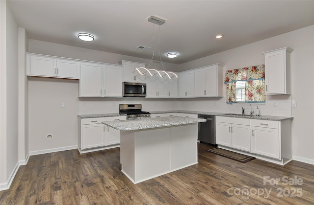 9505 Cotswood Pl, Gastonia, NC 28056 - kitchen featuring appliances with stainless steel finishes, white cabinets, backsplash, a center island, and decorative light fixtures