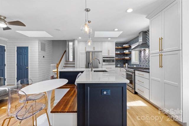 4024 Tyndale Ave, Charlotte, NC 28210 - kitchen with a skylight, wall chimney exhaust hood, stainless steel appliances, a sink, and ceiling fan