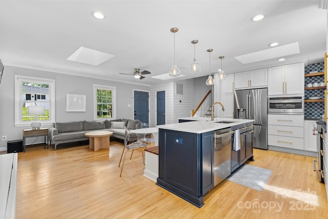 4024 Tyndale Ave, Charlotte, NC 28210 - kitchen featuring a skylight, a sink, appliances with stainless steel finishes, white cabinetry, and light wood-type flooring