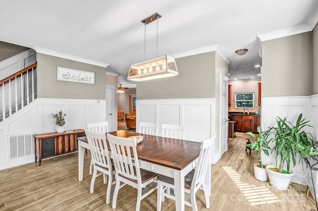 1503 Stoney Ct, York, SC 29745 - dining room with ornamental molding, a decorative wall, a wainscoted wall, light wood-style flooring, and a ceiling fan