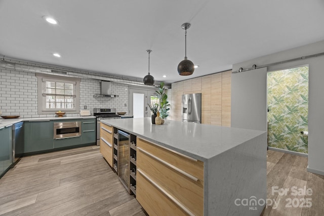 3528 Colony Rd Unit A, Charlotte, NC 28211 - kitchen with wall chimney exhaust hood, appliances with stainless steel finishes, beverage cooler, light wood finished floors, and a center island