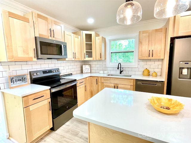 kitchen with appliances with stainless steel finishes, a sink, light brown cabinets, ornamental molding, and light countertops