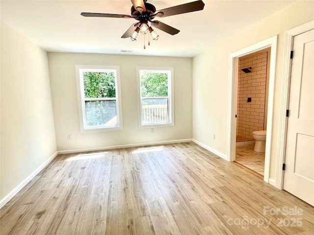 empty room featuring ceiling fan, light wood-type flooring, and baseboards