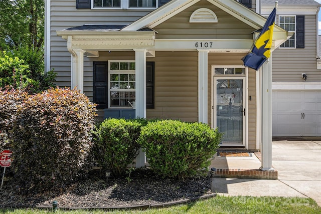 6107 Raisin Tree Ln, Charlotte, NC 28215 - doorway to property featuring an attached garage, concrete driveway, and a porch
