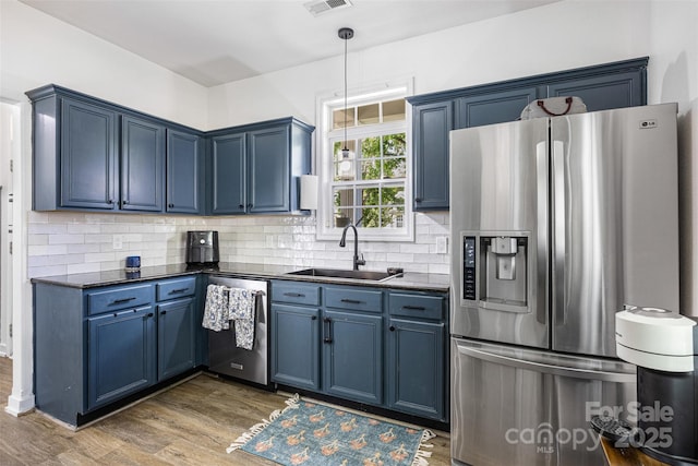 6107 Raisin Tree Ln, Charlotte, NC 28215 - kitchen featuring stainless steel appliances, a sink, blue cabinetry, dark countertops, and dark wood-style floors