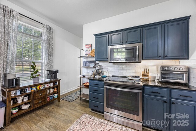 6107 Raisin Tree Ln, Charlotte, NC 28215 - kitchen with stainless steel appliances, blue cabinetry, and wood finished floors