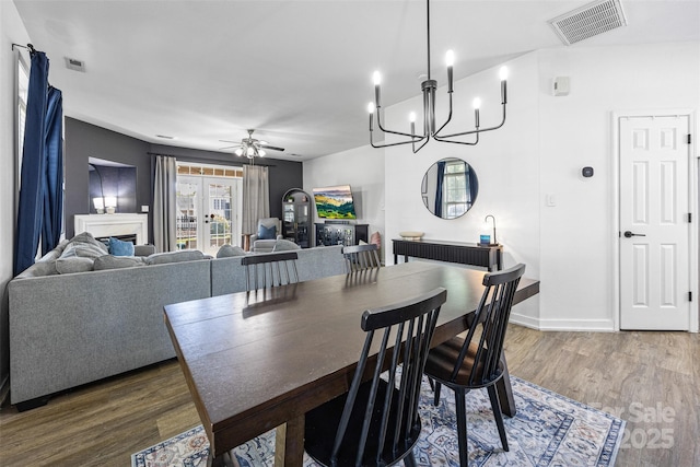 6107 Raisin Tree Ln, Charlotte, NC 28215 - dining room with a fireplace, ceiling fan, wood finished floors, a chandelier, and baseboards