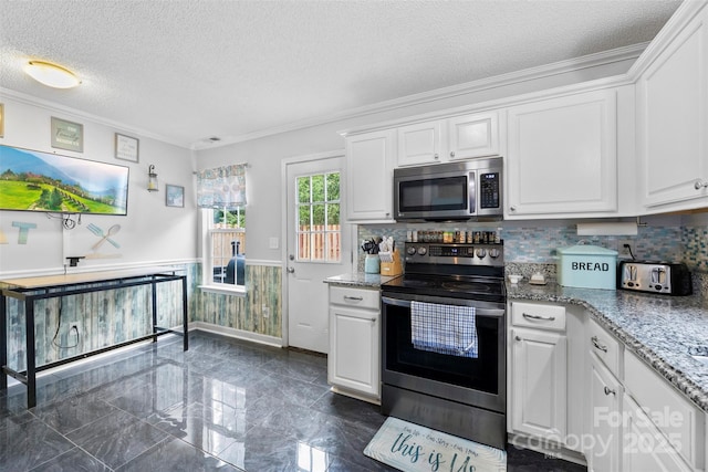 641 Saratoga Dr, Clover, SC 29710 - kitchen with stainless steel appliances, a textured ceiling, wainscoting, white cabinets, and ornamental molding