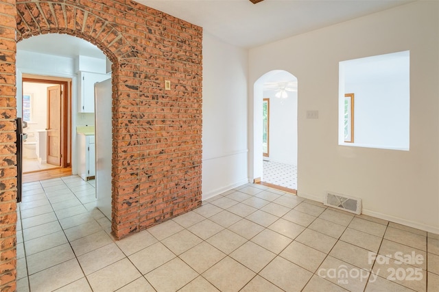 179 Brevard Rd, Asheville, NC 28806 - unfurnished room with arched walkways, light tile patterned floors, ceiling fan, and brick wall