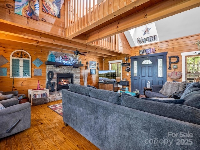 321 River Ridge Parkway, Rutherfordton, NC 28139 - living room with wooden walls, wood-type flooring, a stone fireplace, a ceiling fan, and a high ceiling