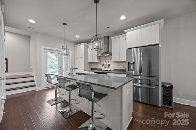336 Uptown W Dr, Charlotte, NC 28208 - kitchen featuring stainless steel appliances, wall chimney range hood, a sink, a kitchen island with sink, and a breakfast bar area