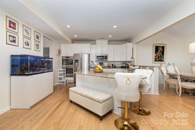 12822 Plumleaf Dr, Charlotte, NC 28213 - kitchen featuring appliances with stainless steel finishes, white cabinetry, light wood finished floors, baseboards, and recessed lighting