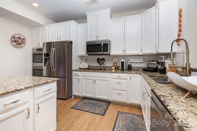 12822 Plumleaf Dr, Charlotte, NC 28213 - kitchen with stainless steel appliances, a sink, light wood finished floors, white cabinets, and recessed lighting