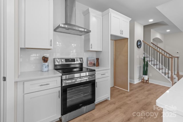 4949 Rimer Rd Unit 4, Concord, NC 28025 - kitchen featuring stainless steel range with electric cooktop, wall chimney range hood, light countertops, white cabinets, and decorative backsplash