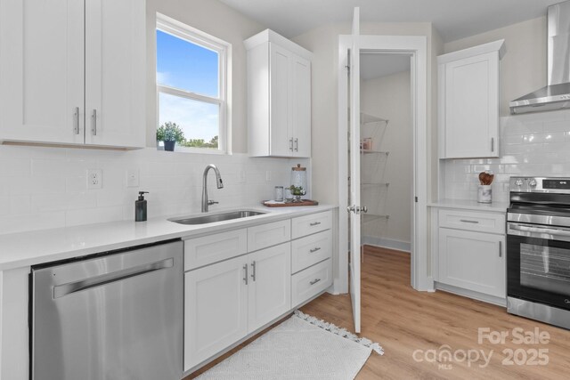 4949 Rimer Rd Unit 4, Concord, NC 28025 - kitchen featuring appliances with stainless steel finishes, wall chimney range hood, white cabinets, tasteful backsplash, and light countertops