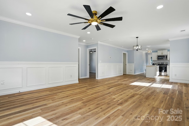 251 Hall Ave NW, Concord, NC 28027 - unfurnished living room with a ceiling fan, light wood-style flooring, a chandelier, wainscoting, and recessed lighting