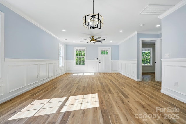 251 Hall Ave NW, Concord, NC 28027 - unfurnished living room with a chandelier, wainscoting, crown molding, light wood finished floors, and a decorative wall