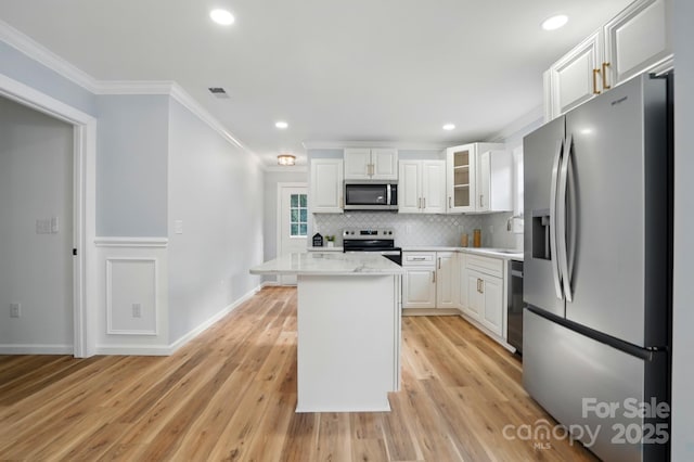 251 Hall Ave NW, Concord, NC 28027 - kitchen with stainless steel appliances, crown molding, white cabinetry, light countertops, and light wood finished floors