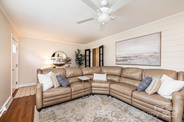 living area featuring ornamental molding, wood finished floors, ceiling fan, baseboards, and wooden walls