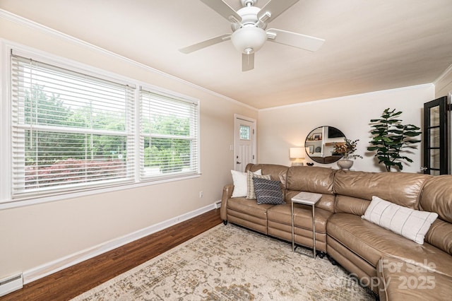 living room featuring baseboards, wood finished floors, ornamental molding, ceiling fan, and a baseboard heating unit
