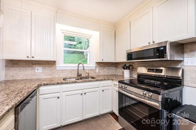 kitchen with stainless steel appliances, a sink, decorative backsplash, white cabinetry, and light stone counters