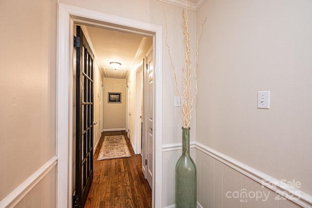 hall with attic access, dark wood-style floors, ornamental molding, wainscoting, and a decorative wall